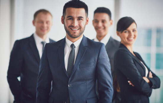 Portrait of confident business partners looking at camera with smiling leader in front